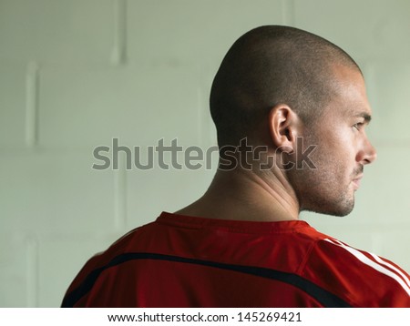Rear view of a bald soccer player against green wall