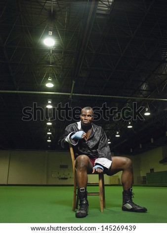 Full length portrait of an African American boxer sitting on chair