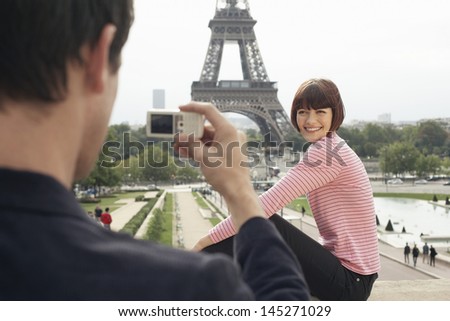 Cropped man photographing woman in front of Eiffel Tower