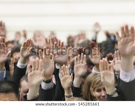 Closeup of business crowd raising hands - stock photo