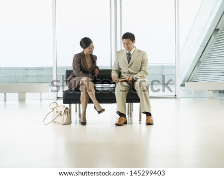 Businesspeople looking over documents on bench in the airport
