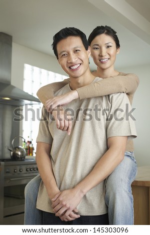 Portrait of a woman sitting on countertop and embracing man from behind