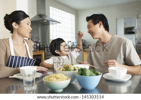 Happy young family enjoying meal at the kitchen table in house