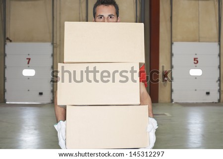 Warehouse worker carrying boxes against loading dock doors