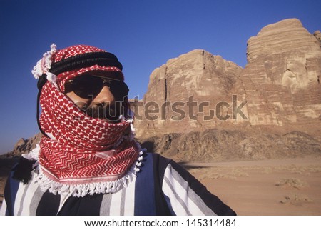 Closeup of an Arab man in turban wearing Sunglasses in desert landscape