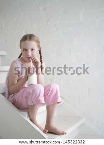 Portrait of a bare feet girl drinking glass of milk on stairs