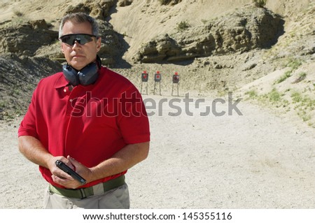 Man holding hand gun at firing range portrait
