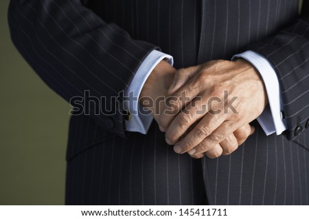 Closeup midsection of a businessman in suit standing with hands clasped