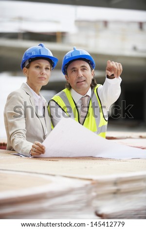 Architect and construction manager discussing plans at site