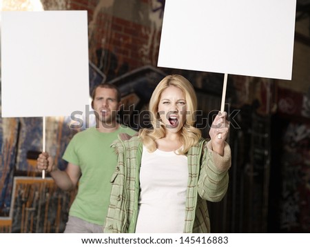 Portrait of a young woman and man holding blank demonstration placards