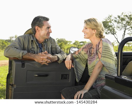 Man and woman talking by the jeep against clear sky