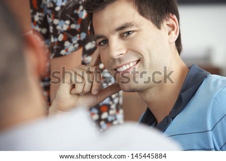 Closeup of a smiling young businessman listening to colleague in meeting