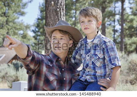 Father pointing out at something to his son in park