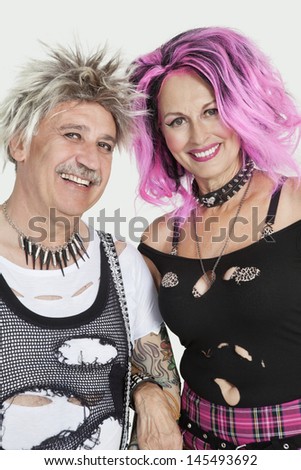 Portrait of senior punk couple standing with arm in arm over gray background