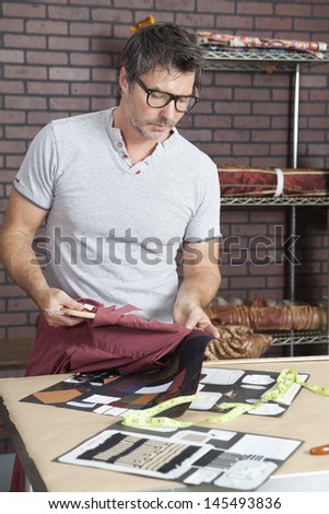 Mature male fashion designer matching color of shirt with cloth swatch
