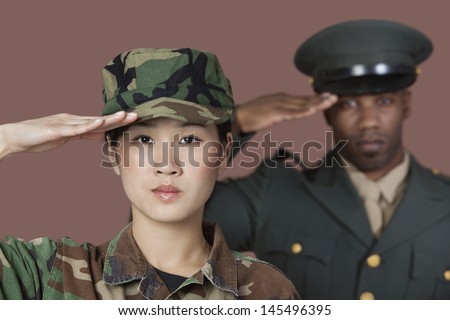 Close-up portrait of young female US Marine Corps soldier with male officer saluting over brown background