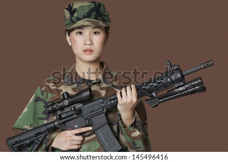 Portrait of beautiful young US Marine Corps soldier with M4 assault rifle over brown background