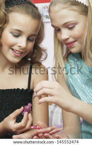 Closeup of a young girl applying nail polish to friend\'s fingernails