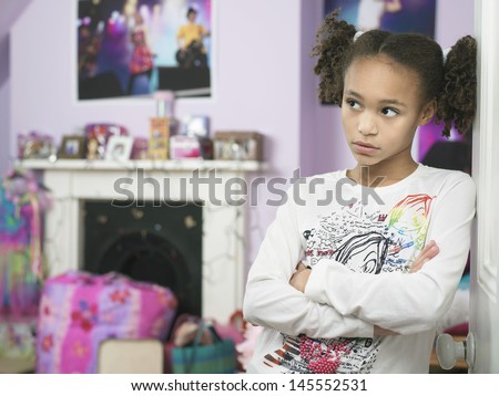 Young girl leaning against door with arms crossed and showing attitude