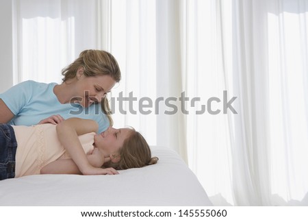 Happy mother and daughter lying in bed