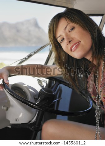 Portrait of happy young woman sitting in driver\'s seat of van