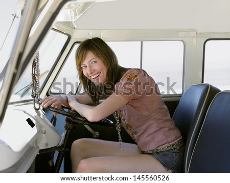 Portrait of beautiful young woman smiling in driver\'s seat of van