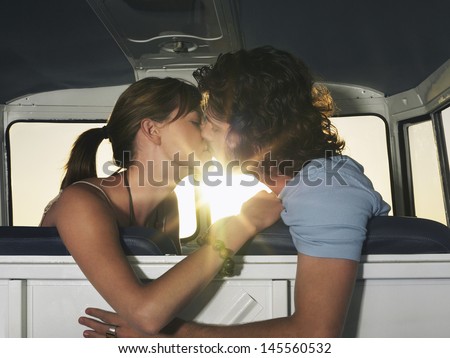 Side View Of Romantic Young Couple Kissing In Campervan