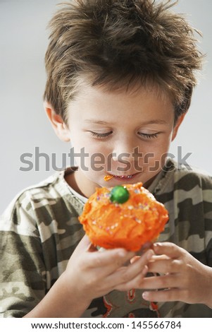 Young boy eating cupcake isolated on gray background