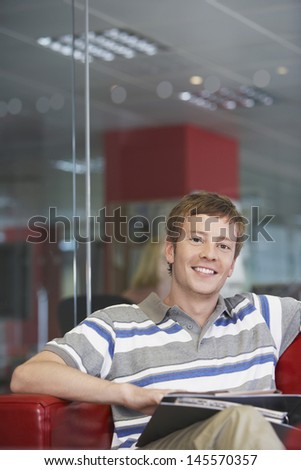 Portrait of a smiling casual young male executive sitting on sofa in office