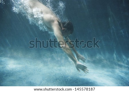 Side view of middle aged man swimming underwater