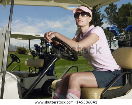 Beautiful female golfer wearing sunglasses in golf cart