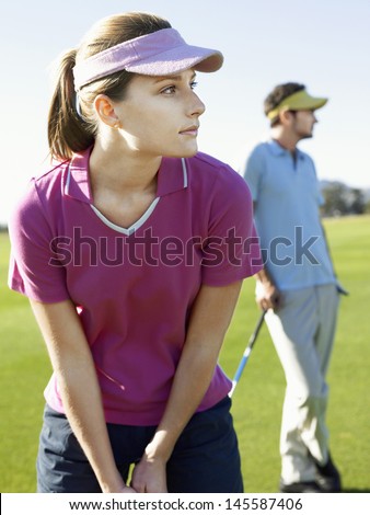 Young woman playing golf with male friend on golfcourse