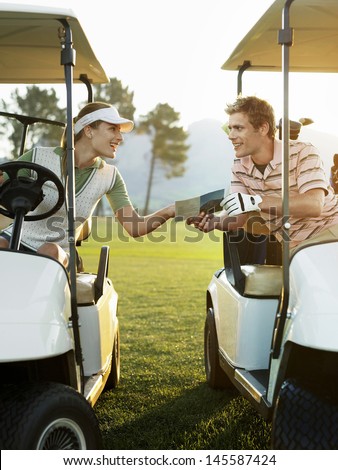 Young golfers sitting in golf carts holding score card on course