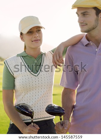 Young female golfer with male friend on golf course