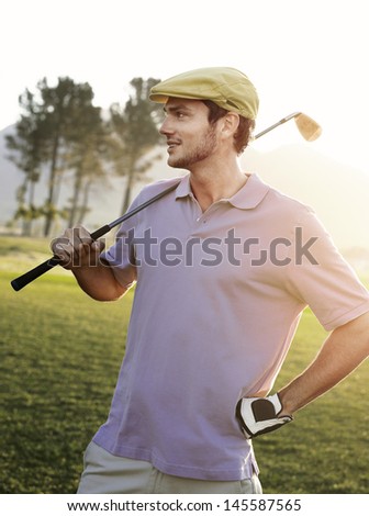 Handsome young male golfer holding club on golf course