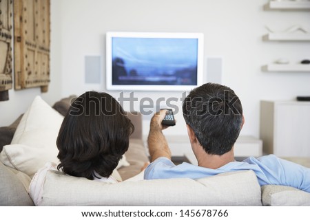 Rear View Of Couple Watching Television In Living Room