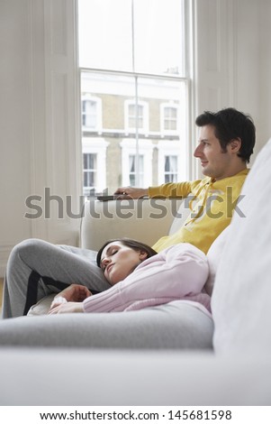 Young woman resting on man\'s lap on couch at home