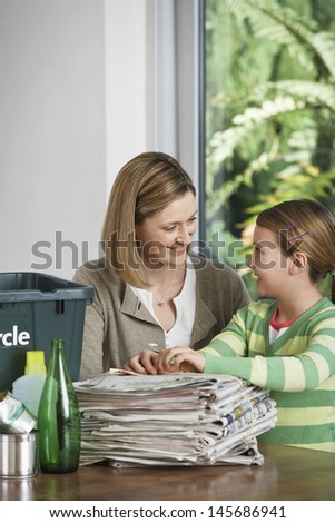 Woman and girl preparing waste paper for recycling at home