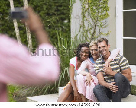 Three multiethnic friends being photographed outdoors