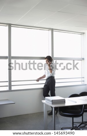 Businessman using mobile phone and looking out of office window