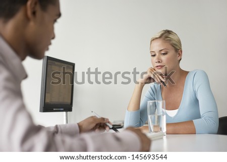 Businesswoman and cropped client sitting at office desk