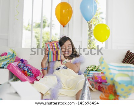 Cheerful young girl opening birthday presents in house