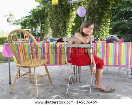 Portrait of a little girl sitting at table after birthday party
