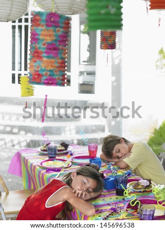 Boy and girl sleeping at outdoor table after birthday party