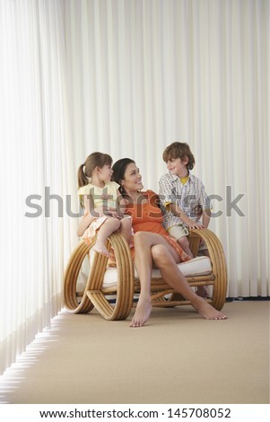 Happy mother with children sitting on armchair in corner of room
