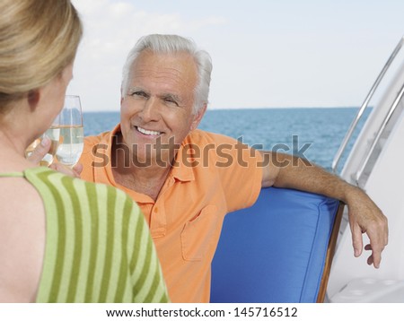Happy middle aged couple toasting champagne on yacht