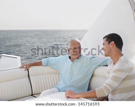 Happy senior man with son relaxing on yacht
