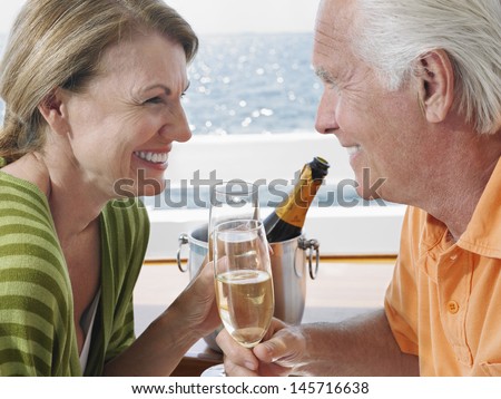 Side view of happy middle aged couple drinking champagne on yacht