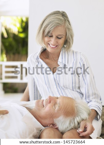 Mature man resting head on woman\'s lap on verandah