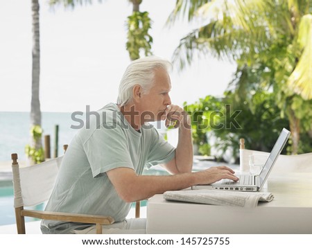Side view of a serious mature man using laptop at outdoor table